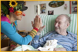 Foto von einem KlinkClowns bei einem Besuch eines Seniors in einem Krankenhaus